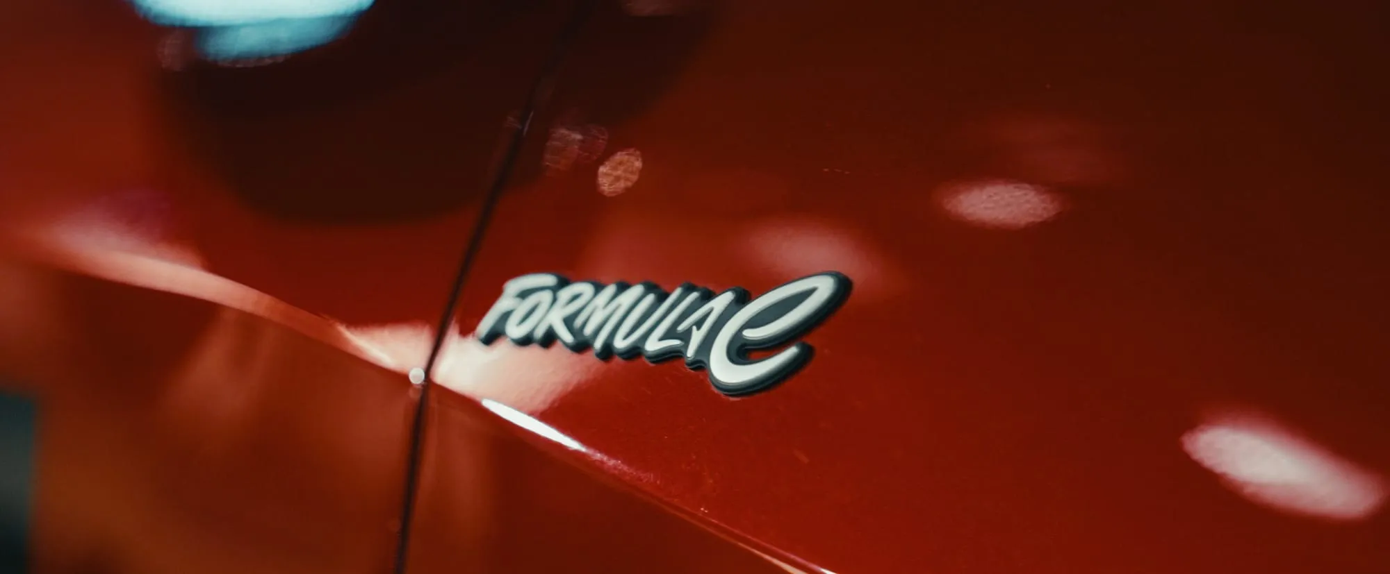 Formula E badge on red bodywork, catching the street light.